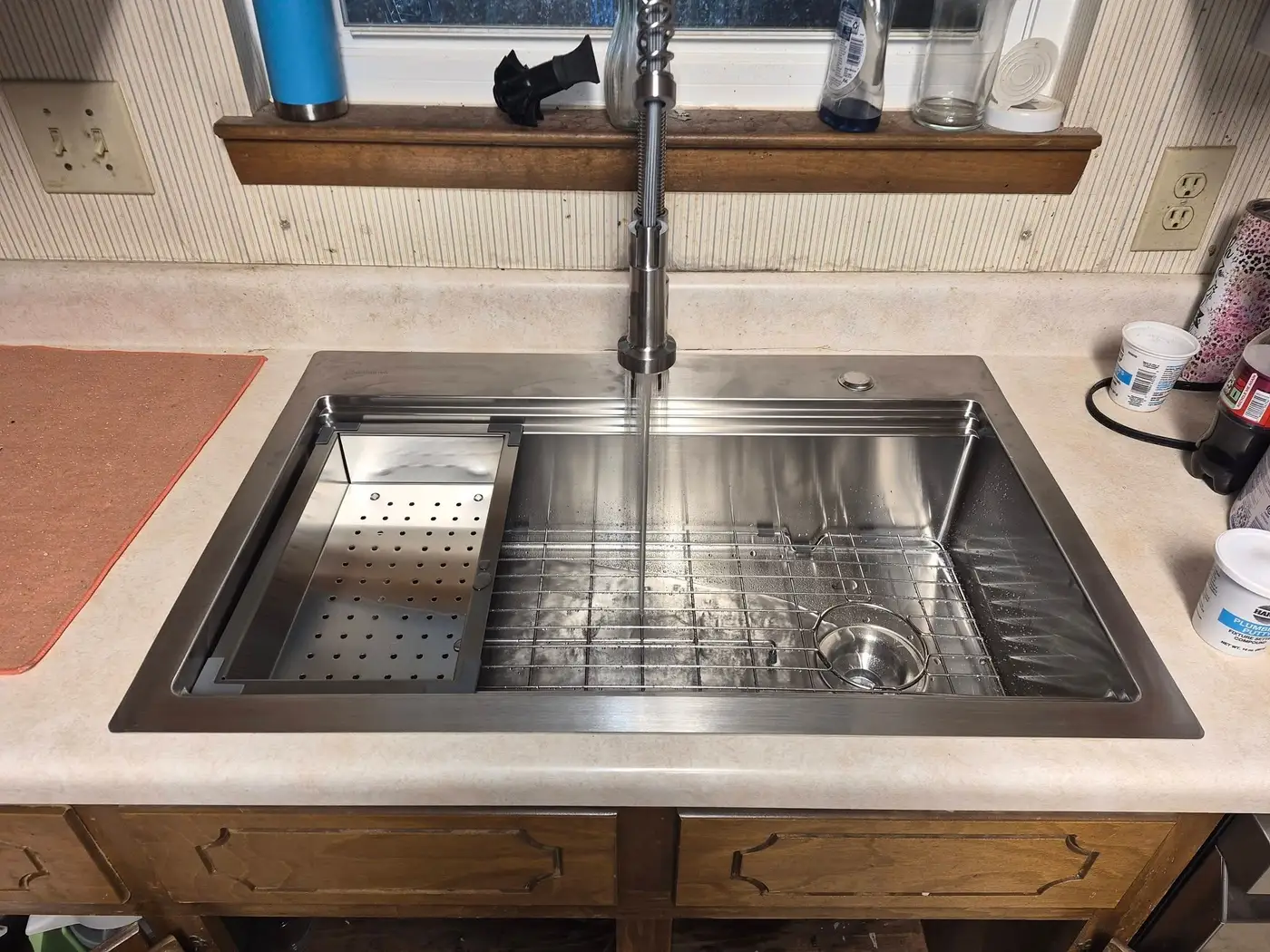 New stainless steel workstation sink with a pull-down faucet installed in a laminate kitchen counter